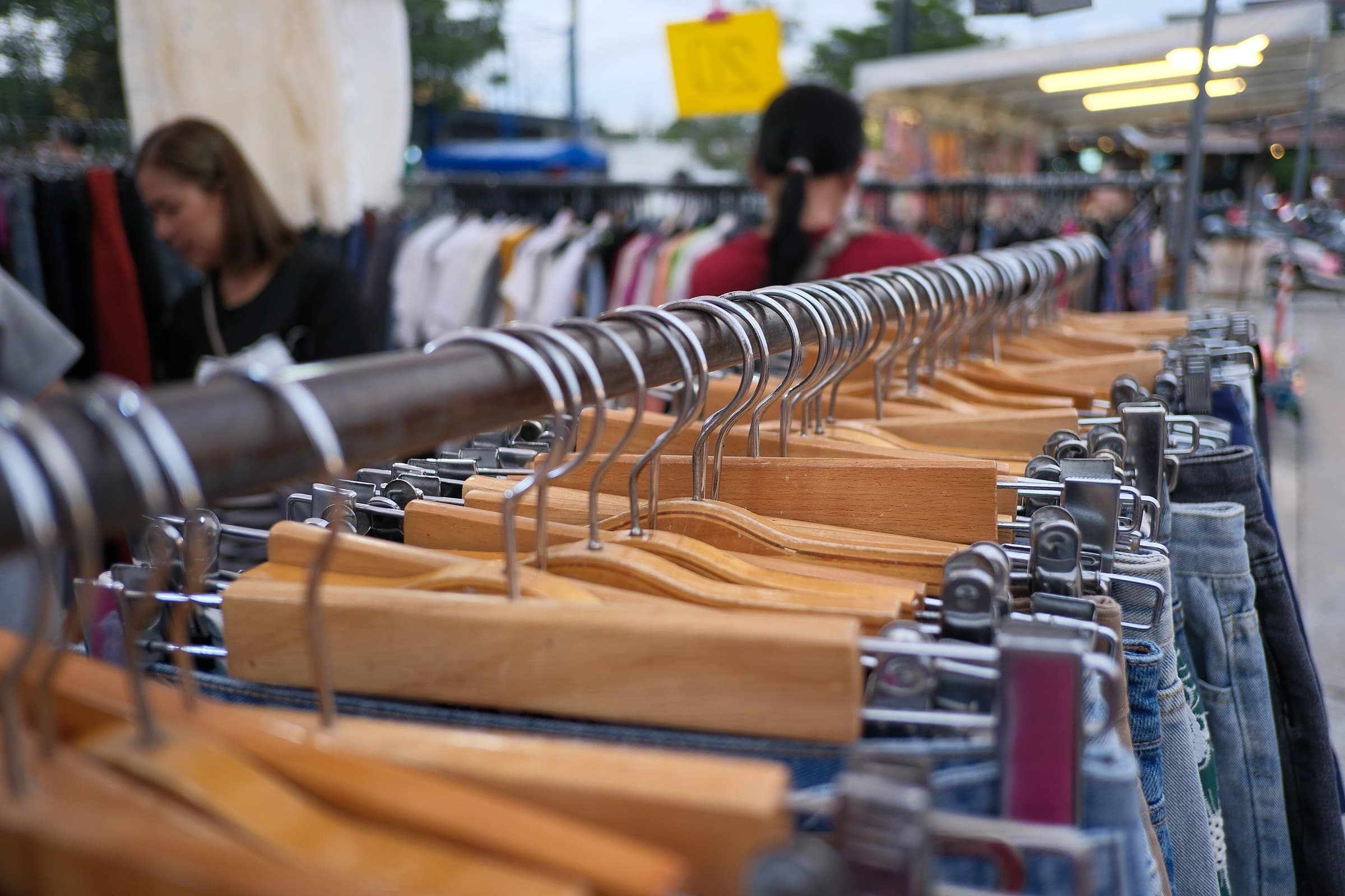 Second-hand jeans on wooden hangers along a market rail